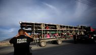 A police officer takes pictures of migrants as they arrive in the back of a truck to a provisional shelter during their journey towards the United States, in Saltillo, Mexico February 3, 2019. Reuters/Daniel Becerril