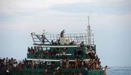 Rohingya migrants bring back food supplies dropped by a Thai army helicopter from sea a boat drifting in Thai waters off the Koh Lipe island in the Andaman sea, May 14, 2015. AFP/Christophe Archambault