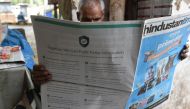 This photo illustration shows a newspaper vendor reading a newspaper with a full back page ad from WhatsApp intended to counter fake information in New Delhi on July 10, 2018. AFP / Prakash Singh