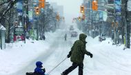 A man pulls a child in a sled during a winter snow storm in Ottawa, Ontario, Canada, February 13, 2019. Reuters/Chris Wattie