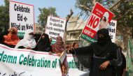 A supporter of the Pakistan Sunni Tehreek (PST) organization holds a burning Valentine's card while other carry placards and a banner during a protest against Valentine's Day celebrations, in Hyderabad on February 14, 2019.  AFP / Akram Shahid
