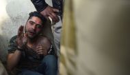 An injured man that an angry mob had attacked, believing him to be a Kashmiri who had shouted pro-Pakistan slogans, is shielded by Indian policemen in New Delhi on February 17, 2019.  AFP / Sajjad Hussain 