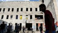 FILE PHOTO: Migrants stand in front of a dorm destroyed during the Bosnian 1992-1995 war, in Bihac, Bosnia and Herzegovina August 20, 2018. REUTERS/Igor Pavicevic