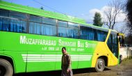 A Pakistani Kashmiri walks past a bus doing the Muzaffarabad-Srinagar Bus Service parked on a street, in Muzaffarabad, the capital of Pakistan's controlled Kashmir on February 19, 2019 following a shut down of the bus service connecting the cities. AFP / 