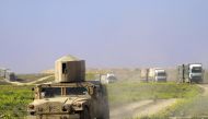 Members of the Kurdish-led Syrian Democratic Forces (SDF) escort trucks carrying men, identified as Islamic State group fighters who surrendered as they are being transported out of IS's last holdout of Baghouz in Syria's northern Deir Ezzor province, on 