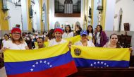 Supporters of Venezuelan opposition leader Juan Guaido, who many nations have recognized as the country's rightful interim ruler, hold Venezuelan flags during a meeting at the Queen of the Most Holy Rosary Cathedral in Willemstad on the island of Curacao,