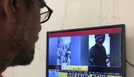 A man looks at a television screen displaying the pictures of the Indian pilots, said to be captured by Pakistan after shooting down two Indian planes, in Karachi, Pakistan February 27, 2019. Reuters/Akhtar Soomro