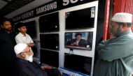 Shopkeepers watch the speech of Pakistani Prime Minister Imran Khan. REUTERS/Akhtar Soomro