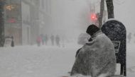 A homeless man asks for money outside a donut shop during white-out, blizzard-like conditions in a winter nor'easter snow storm in Boston, Massachusetts. February 9, 2017. Reuters/Brian Snyder
 