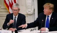 US President Donald Trump reaches out to Apple CEO Tim Cook as they participate in an American Workforce Policy Advisory Board meeting in the White House State Dining Room, March 6, 2019. Reuters/Leah Millis