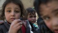 Syrian children sit in the back of a truck driven by White Helmets as they flee their homes in the town of Beit Sawa in eastern Ghouta region on March 4, 2018. AFP/Abdulmonam Eassa