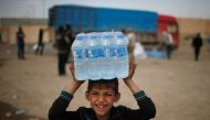 A displaced Iraqi boy smiles after receiving water in western Mosul, Iraq, March 28, 2017. Reuters/Suhaib Salem