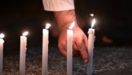 A well-wisher helps to light 49 candles as he pays respects to victims outside the hospital in Christchurch on March 16, 2019, after a shooting incident at two mosques in the city the previous day. AFP / Anthony WALLACE