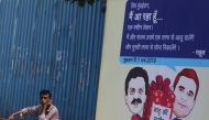 A man speaks on a phone next to a hoarding with cartoons of India's main opposition Congress Party President Rahul Gandhi and Sanjay Nirupam, President of the Mumbai Regional Congress Committee, alongside a road in Mumbai, India, February 22, 2019. REUTER