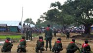 Myanmar personnel stand guard while a mob looks on following unrest at an Internally Displaced People camp for Muslim Rohingyas on the outskirts of Sittwe town in Rakhine State on August 9, 2013. (AFP) 
