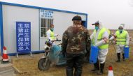 Workers in protective suits disinfect a vehicle at a checkpoint on a road leading to a farm owned by Hebei Dawu Group where African swine fever was detected, in Xushui district of Baoding, Hebei province, China February 26, 2019. Reuters/Hallie Gu