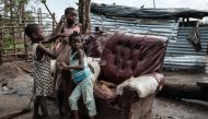Children play in front of a house destroyed by the winds of cyclone Idai in Beira, Mozambique, on March 27, 2019.  AFP / Yasuyoshi Chiba  