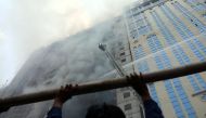 A person looks on as firefighters attempt to extinguish a fire at a multi-storey commercial building in Dhaka, Bangladesh, March 28, 2019. REUTERS/Mohammad Ponir Hossain