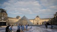 French contemporary artist and photographer Jean Rene (L), aka JR, is helped by volunteers during preparation works of his installation in the main courtyard Cour Napoleon of the Louvre Museum in Paris on March 27, 2019, as part of the 30th anniversary ce