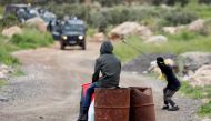 A Palestinian watches as other hurls stones at Israeli troops during a protest marking the Land Day in al-Mughayer village, in the Israeli-occupied West Bank March 29, 2019. Reuters/Mohamad Torokman