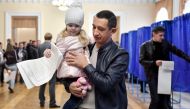A young girl casts the ballot of a man at a polling station in Kiev on the first round of Ukraine's presidential election, on March 31, 2019.   / AFP / Sergei SUPINSKY
