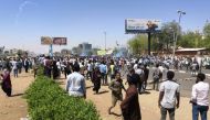 Sudanese protesters run for cover from teargas outside the military headquarters in the capital Khartoum on April 7, 2019.  AFP 