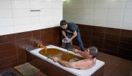 A man bathes in a tub filled with Naftalan crude oil during a treatment session at Sehirli Naftalan Health Center, some 300 kilometres from Baku, on March 21, 2019.  AFP / Mladen Antonov 