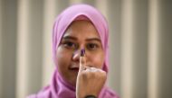 An Indonesian woman, living in Malaysia, shows her inked finger after casting her overseas ballot in their embassy ahead of the country's April 17 general election, in Kuala Lumpur on April 14, 2019. / AFP / Mohd RASFAN 