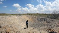 A fighter loyal to Libya's Government of National Accord (GNA) waves from a crater reportedly caused by an air strike west of the city of Aziziah, some 60 kilometres southwest of the capital Tripoli, on April 14, 2019. AFP / Mahmud Turkia
 