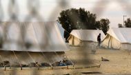 A Syrian refugee walking in between tents at a reception centre in Kokkinotrimithia on the outskirts of the Cypriot capital Nicosia on March 07, 2017. AFP/Iakovos Hatzistavrou