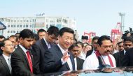 In this file photo taken on September 17, 2014, Chinese President Xi Jinping (C) waves as he leaves alongside Sri Lanka's then-president Mahinda Rajapaksa (R) after formally opening the start of work on the Chinese-funded Port City on reclaimed land in Co