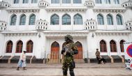 Sri Lankan Special Task Force soldiers stand guard in front of a mosque as a Muslim man walks past him during the Friday prayers at a mosque, five days after a string of suicide bomb attacks on Catholic churches and luxury hotels across the island on East