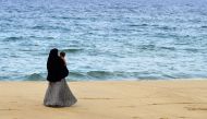 In this picture taken on April 25, 2019, a Sri Lankan Muslim woman walks along a beach with her child in Kattankudy. AFP / Lakruwan Wanniarachchi