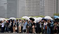 People hold umbrellas to shelter themselves from the rain as they gather outside the Imperial Palace, where the abdication ceremony for Japan's Emperor Akihito will take place, in Tokyo on April 30, 2019.  AFP / Charly TRIBALLEAU