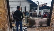 An armed plainclothes policeman (L) secures the area around Siak prison in Siak Sri Indrapura in Riau province on May 11, 2019 after rioting and a fire broke out at the detention centre leading to a prison break. AFP / WAHYUDI