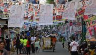 Residents walk past posters of candidates for the midterm elections near a polling precinct in Manila on May 13, 2019. AFP / TED ALJIBE