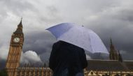 A woman looks towards dark clouds over the Houses of Parliament in central London August 11, 2014. Reuters/Luke MacGregor 