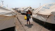 FILE PHOTO: A Venezuelan migrant child carries a broom and a bucket while he walks in a camp run by the UN refugee agency UNHCR in Maicao, Colombia May 7, 2019. Picture taken May 7, 2019. REUTERS/Luisa Gonzalez