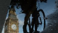 Big Ben is reflected in a puddle as a cyclist rides by in London on 27 June, 2016. AFP/Leon Neal