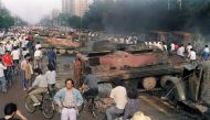 In this file photo taken on June 4, 1989, residents gather near the smoking remains of over 20 armoured personnel carriers burnt by demonstrators during clashes with soldiers near Tiananmen Square in Beijing.  AFP / Manny Ceneta 