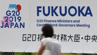 A woman walks past a banner for the upcoming G20 Finance Ministers and Central Bank Governors meeting in Fukuoka on June 7, 2019. / AFP / Toshifumi KITAMURA