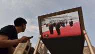 A man watches news footage of Chinese President Xi Jinping (R) being greeted in Pyongyang by North Korean leader Kim Jong Un, on a large screen outside a shopping mall in Beijing on June 20, 2019.(AFP / GREG BAKER)