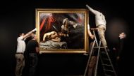 Workers hang on a wall a painting believed by some experts to be Caravaggio's 