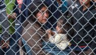 Migrants are gathered inside the fence of a makeshift detention center in El Paso on March 27. 