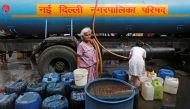 A woman stands after filling her containers with drinking water from a municipal tanker in New Delhi, India, June 28, 2019. Reuters/Adnan Abidi