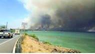 A plume of smoke spreads across the sky during a wildfire in Kihei, as vehicles move along a road in Maui, Hawaii, in this still image taken from a July 11, 2019 video from social media. Traci Teel Szymanski/via Reuters
