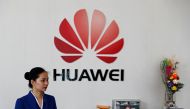 An employee stands next to the logo of Huawei in Shenzhen, Guangdong province, China, March 29, 2019. Reuters/Tyrone Siu
