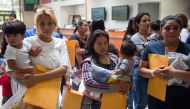 Immigrants wait to head to a nearby relief center after being dropped off at a bus station shortly after release from detention in McAllen, Texas on June 17, 2018. AFP/Loren Elliott
