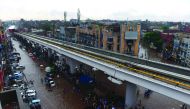 Pakistani commuters and pedestrians cross a flooded street after heavy monsoon rains in Lahore on July 16, 2019. In Pakistan-administered Kashmir, officials said at least 23 people were killed after heavy rain triggered flash floods and damaged more than 