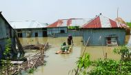 People walk in floodwaters as they transport belongings on a makeshift raft following heavy monsoon rains at a flood affected area of Gaibandha District, in Northern Bangladesh, on July 19, 2019. AFP / Rehman Asad
